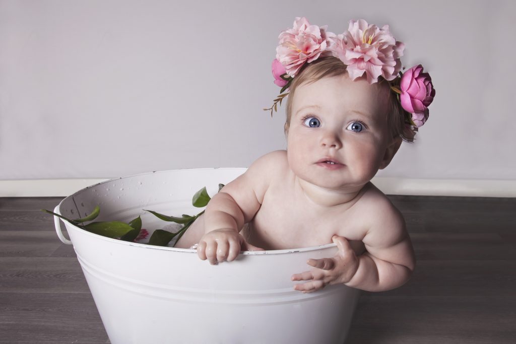 Girl in bath filled with milk and pink flower crown on her head