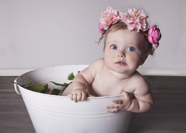 Girl in bath filled with milk and pink flower crown on her head