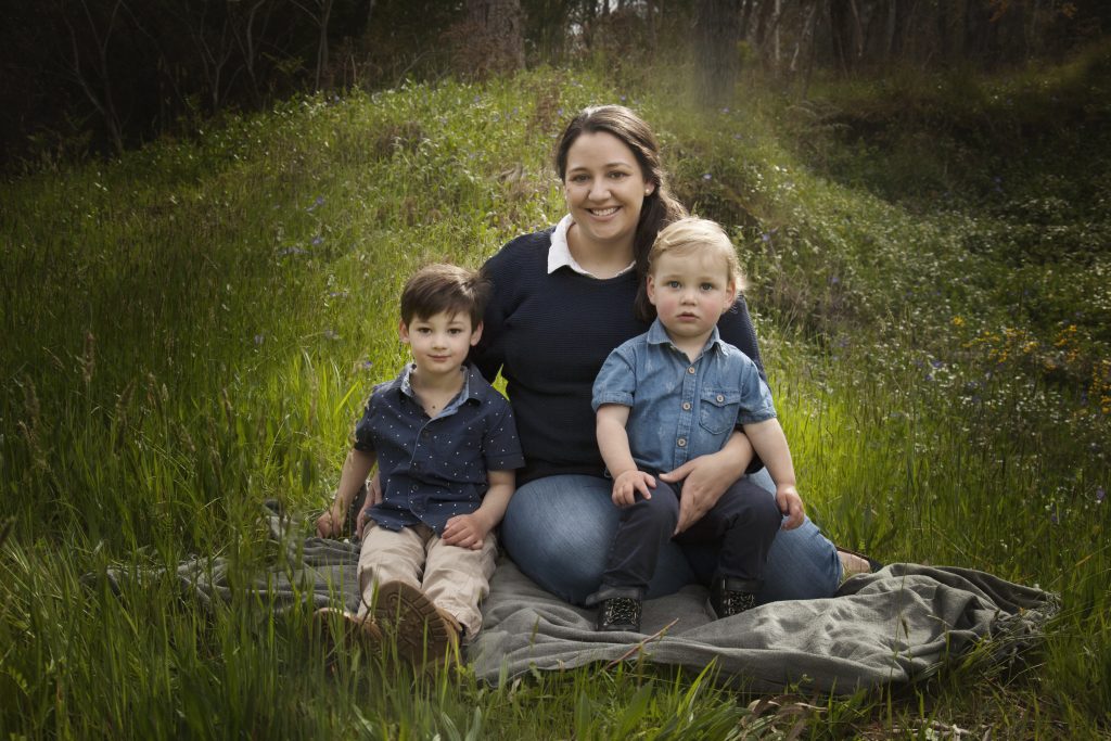 Mother and two boys sitting on grass family photo