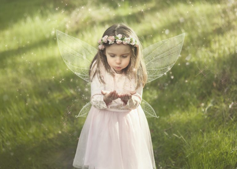 Girl with wings in pretty dress blowing a glittery kiss