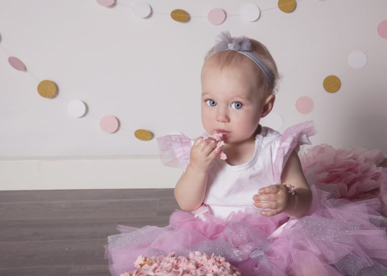 Girl eating her cake in a pink and gold themed photo session