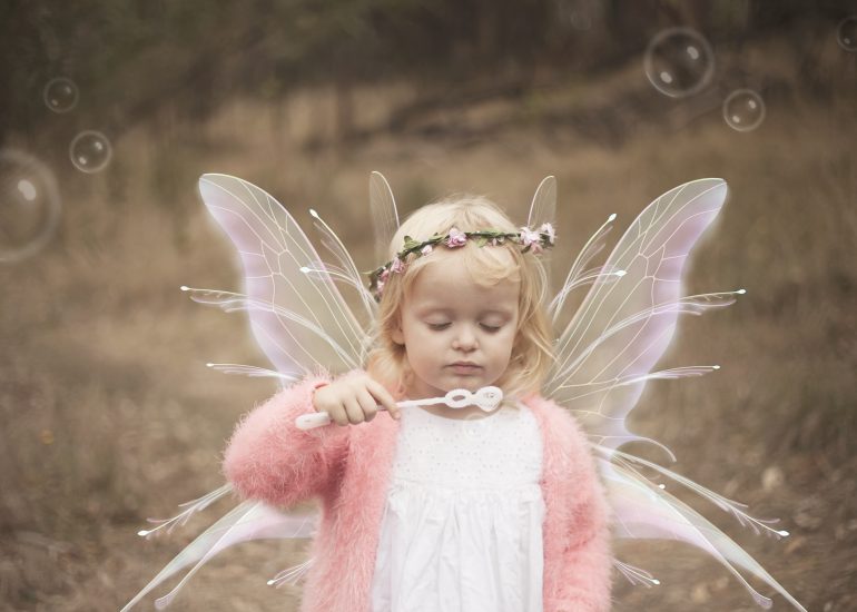 Girl with fairy wings blowing bubbles