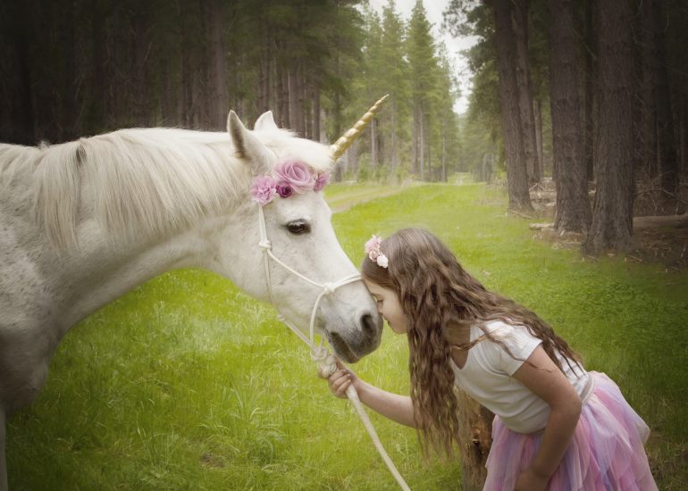 Girl kissing unicorn on the nose