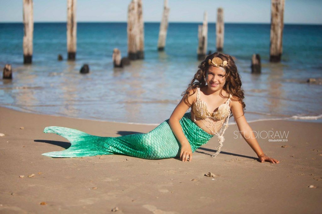 Girl in green mermaid tail on the beach